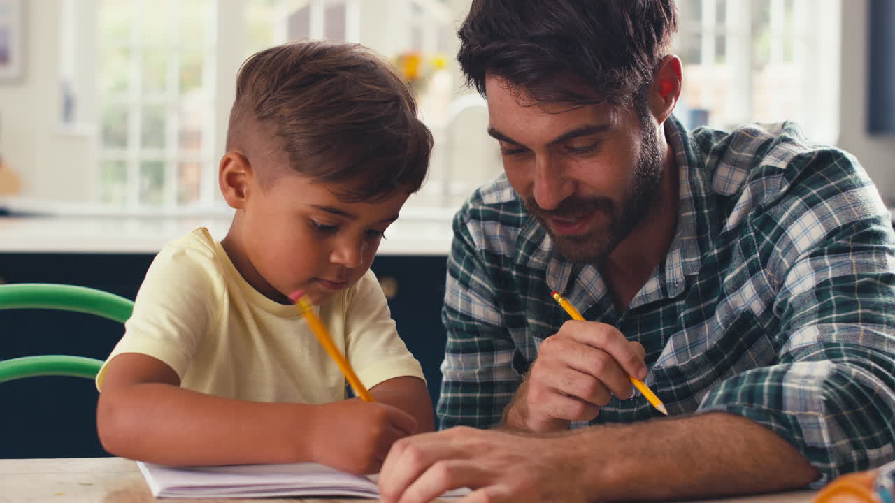 padre en casa en la cocina en la mesa ayudando al hijo con la tarea