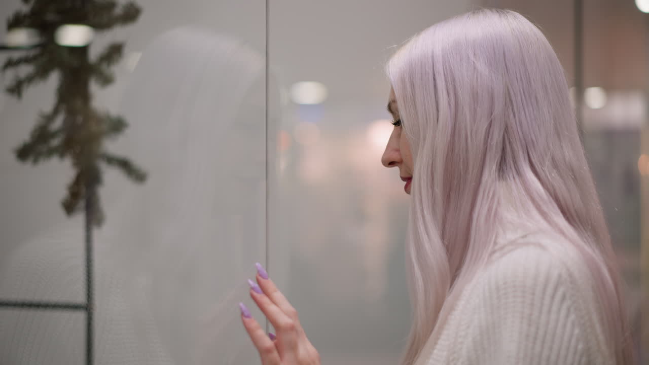 side view modern trendsetter walking toward boutique window display, placing manicured hand on glass in admiration, reflection of interior lights and mannequin dress creating elegant retail moment