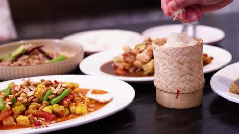 hands serving sticky rice with colorful dishes