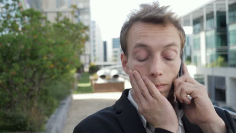 Un-Hombre-Serio-Hablando-Por-Teléfono-Afuera,-Luciendo-Decepcionado