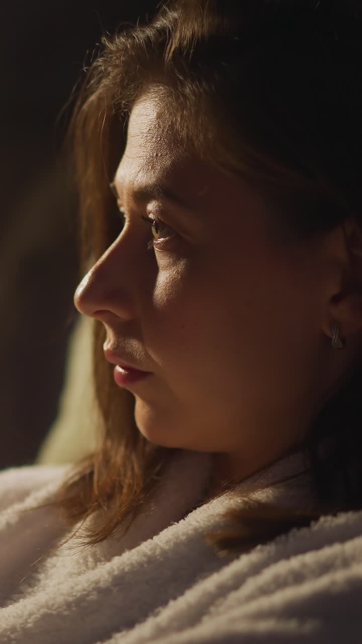 Woman looking out of window on calm night overcomes by sense of melancholy and feels pain of loneliness. Lonely female calms down and relaxes closeup