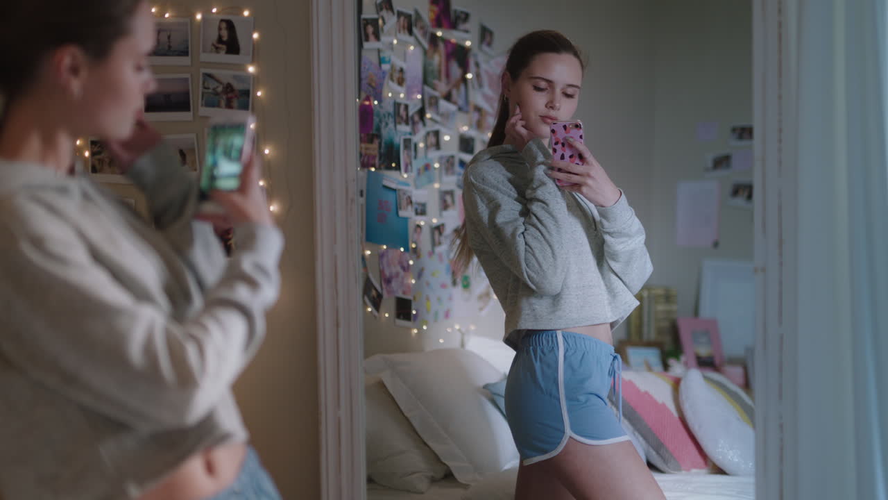 아름다운 십대 소녀가 스마트폰을 사용하여 셀카 사진을 찍고 거울에 포즈를 취하고 소셜 미디어에서 세련된 패션을 공유하고 집에서 주말을 즐기고 십대 자아 이미지