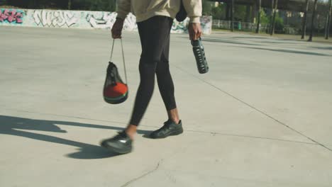 crop ethnic sportsman with gear walking in park