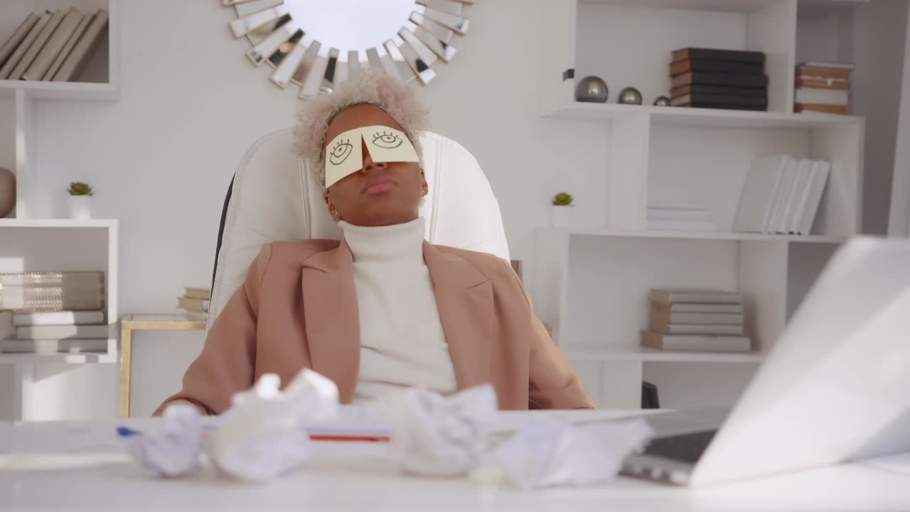 Tired african american businesswoman with memo notes on eyes napping in office