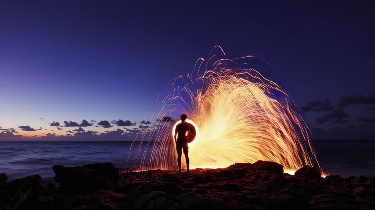 Person Silhouetted Against a Cascade of Sparks from Steel Wool Light Painting on a Beach at Dusk