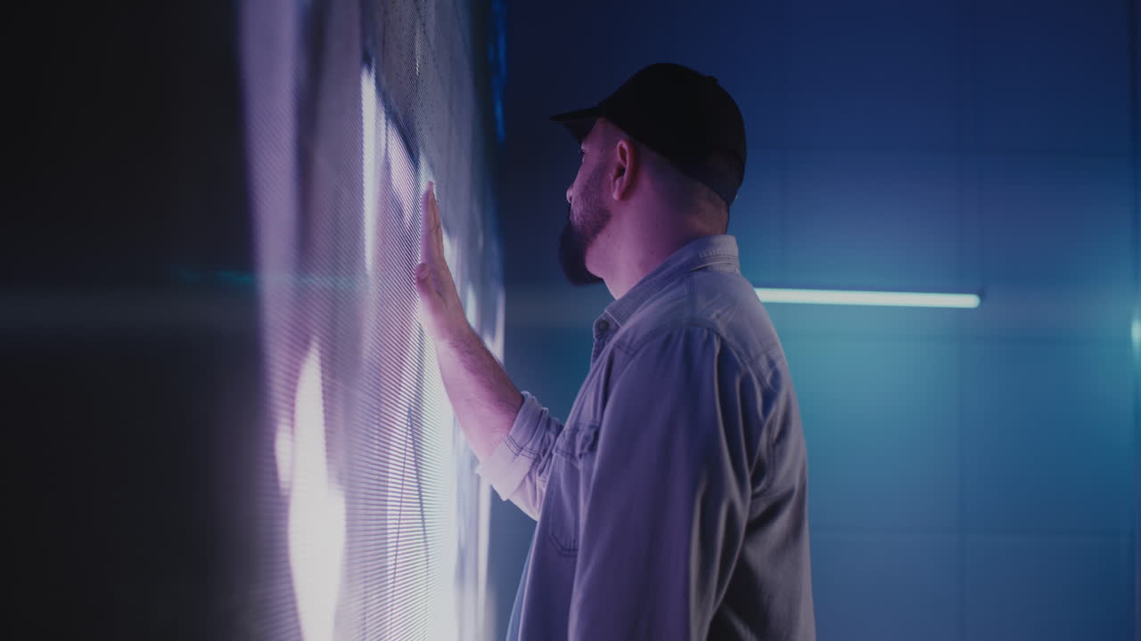 Man interacting with a large interactive LED wall display.