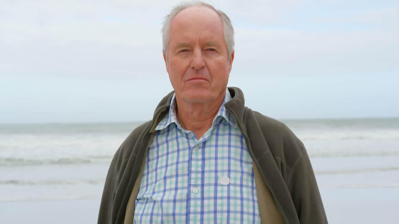 vista frontal de un anciano caucásico de pie en la playa 4k