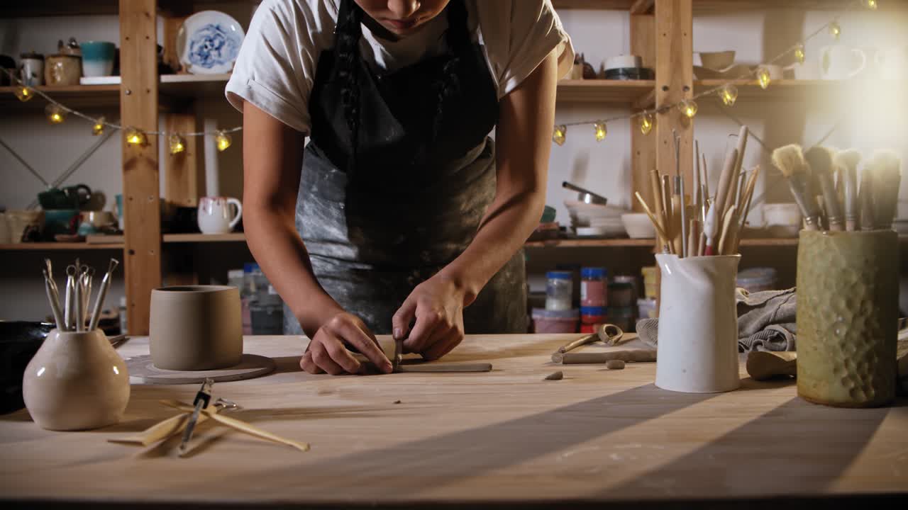 joven alfarera cortando un pedazo de arcilla para un mango