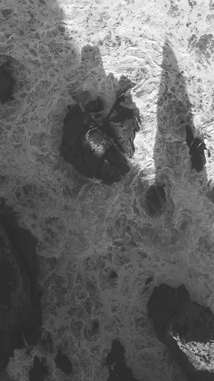 Scenic morning aerial drone shot of Praia da Ursa’s rocky cliffs near Cabo da Roca, Portugal. vertical video. Black and white