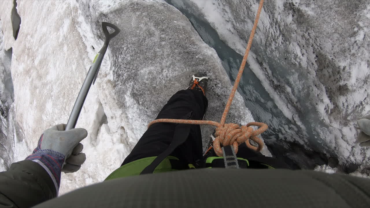 Feet of a mountaineer walking on a glacier, he crosses a deep crevasse, equipped with crampons and rope, ice axe, switzerland