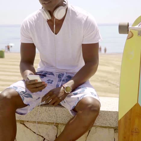 black man checking his phone while seated on wall