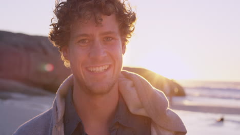 portrait of attractive man smiling on beach at sunset in slow motion