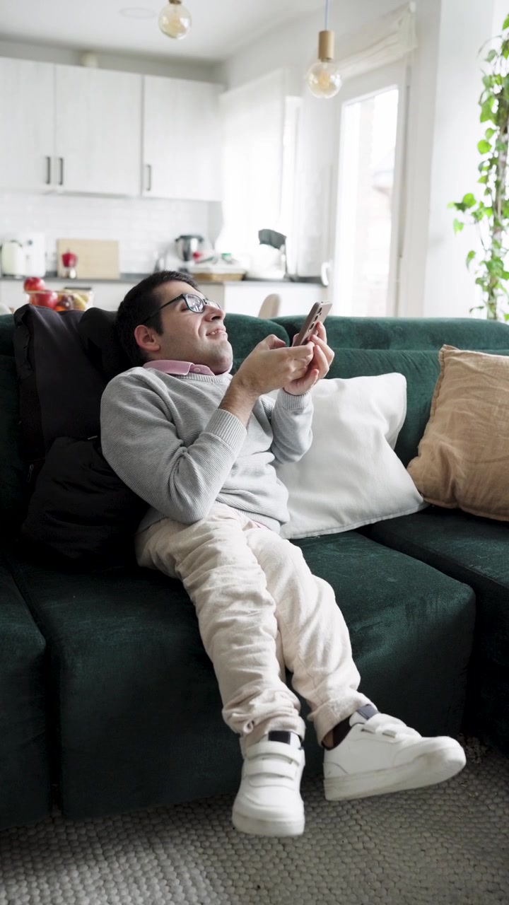 Giovane uomo che si rilassa sul divano e usa lo smartphone a casa