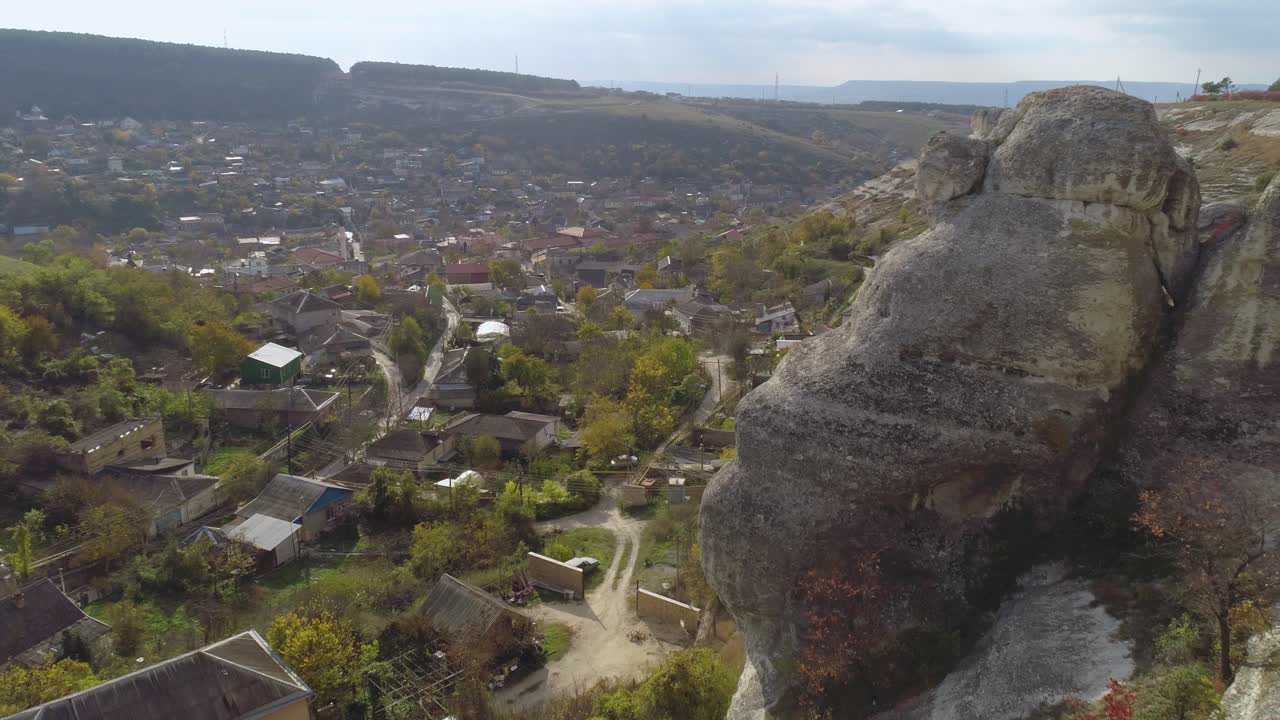 vista aérea de una aldea ubicada en un valle con una gran formación rocosa