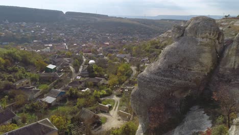 aerial view of a village nestled in a valley with a large rock formation