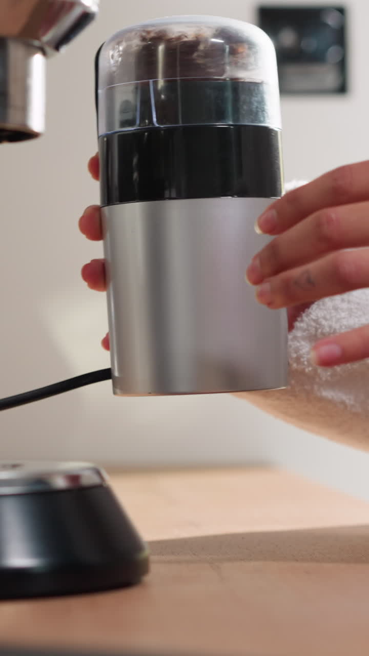 여성은 테이블에서 커피 콩을 고, 테리 로브를 입은 여자는 집에서 는 기계에서 을 습니다.