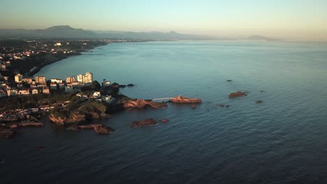 footbridge connecting islet rock of virgin at coast, biarritz at sunset, france