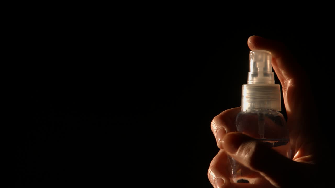 Close-up of Hand Spraying Mist from a Clear Bottle