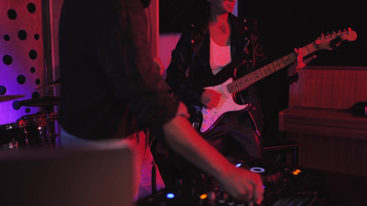Musicisti che suonano la chitarra elettrica e il mixer da DJ in uno studio illuminato al neon