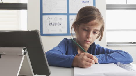 in school, boy using tablet and writing in notebook, focusing on studies