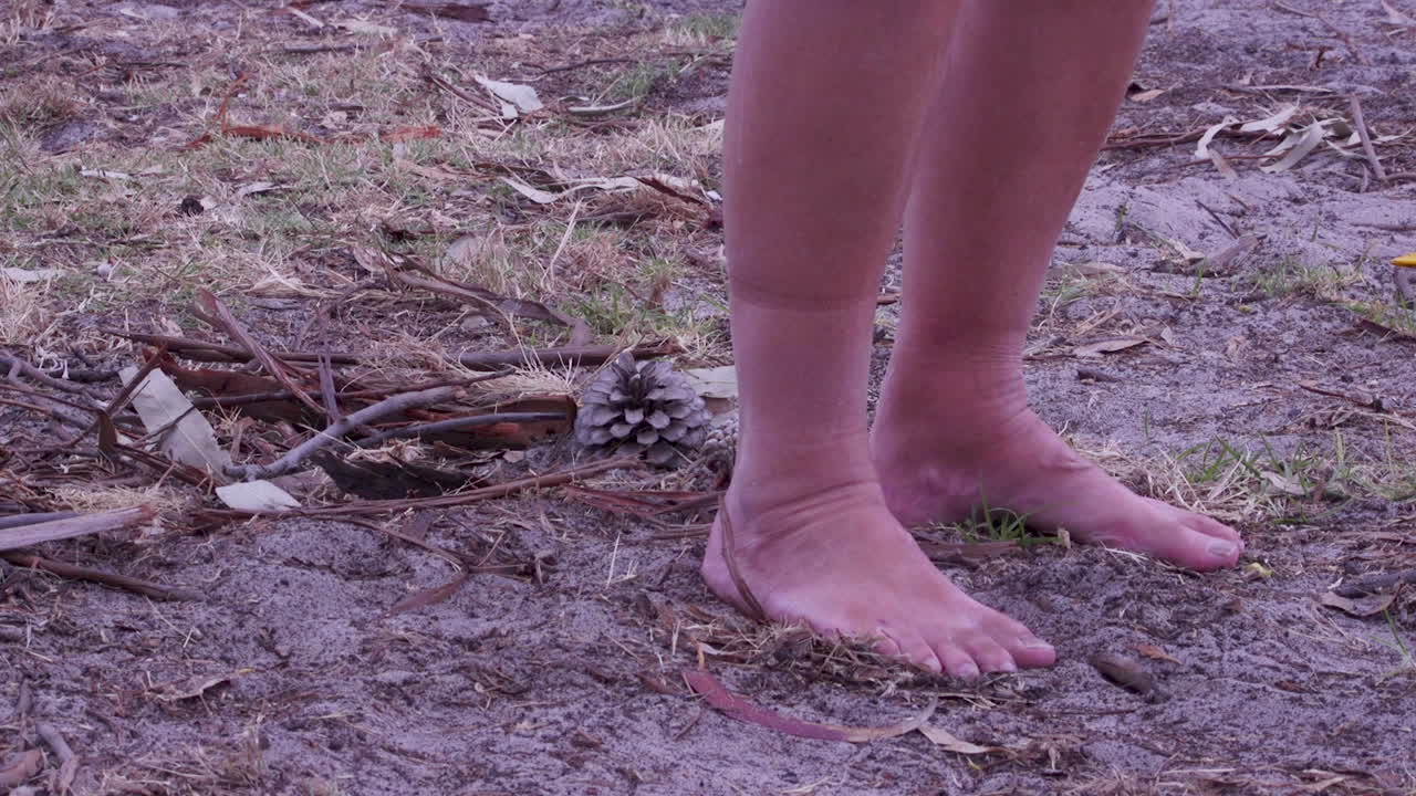 솔방울 두 개를 지나 흙길을 맨발로 걷는 사람