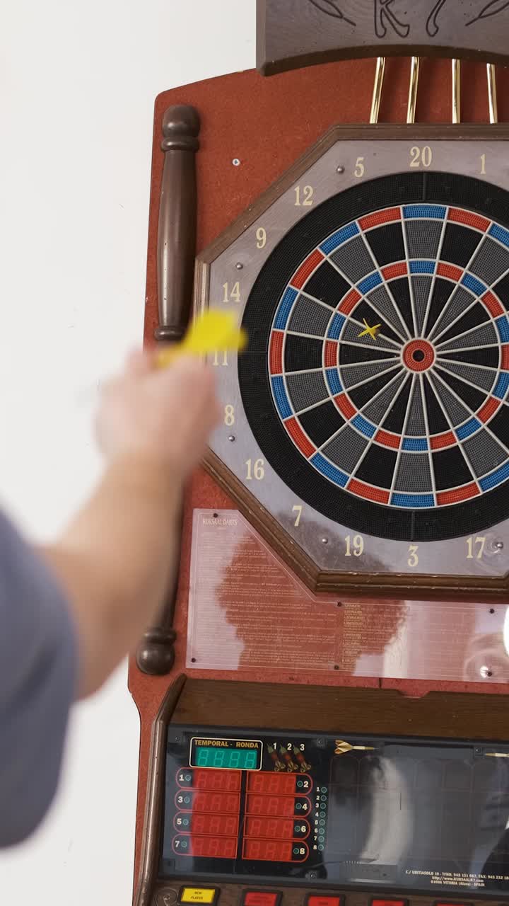Cheerful man playing game of dart with friends at home