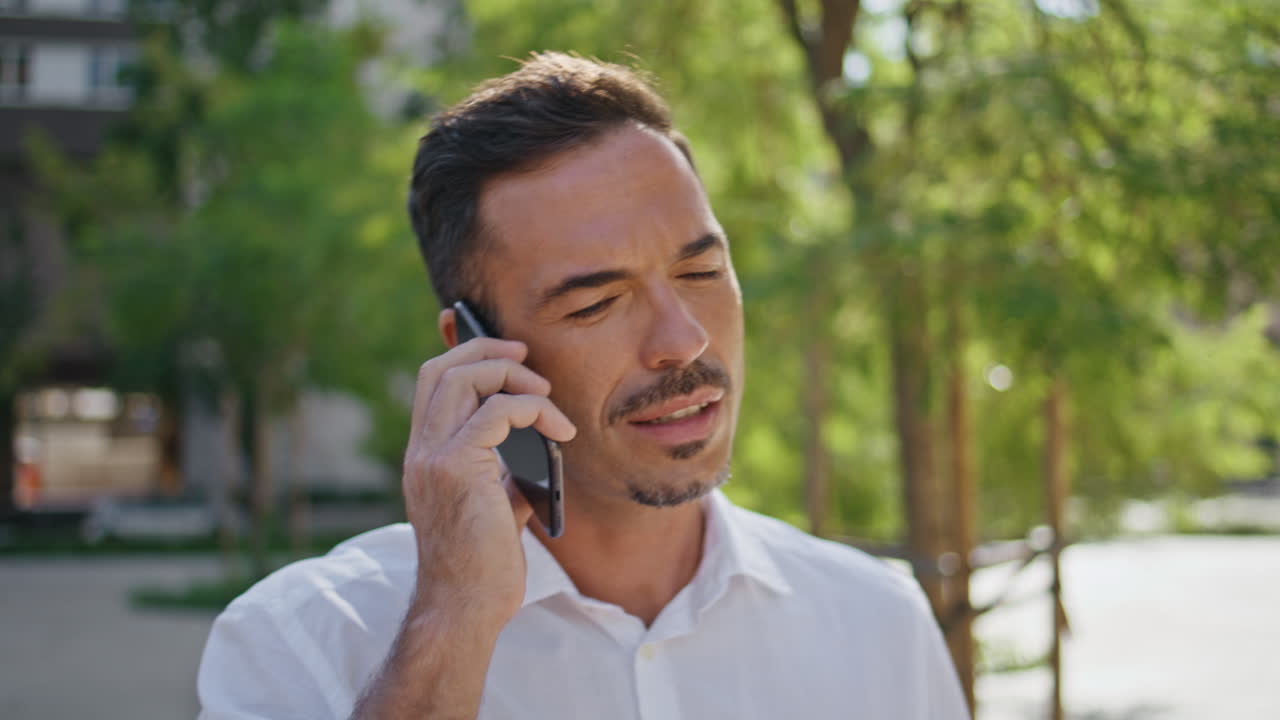 Tanned man answering phone call summer green city closeup. Businessman talking