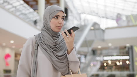 woman in hijab talking on smartphone in shopping mall