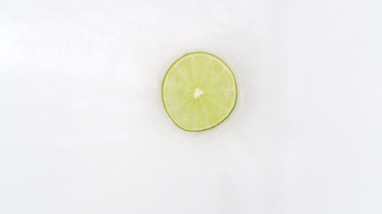 sobre un fondo blanco cortado en rebanadas de cal rociadas con spray de agua. jugosas cal frescas en cámara lenta.