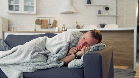 man feeling sick on the couch at home with cold and flu symptoms. pandemic.