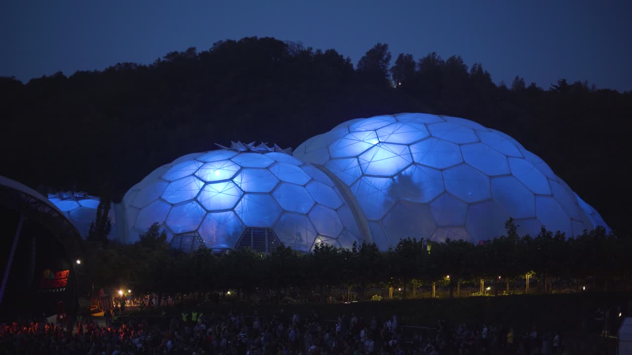 Eden Sessions At Night. Crowd Of People Watching Outdoor Live Music Concert At The Eden Project In Cornwall, UK. Illuminated Biomes In Background. aerial