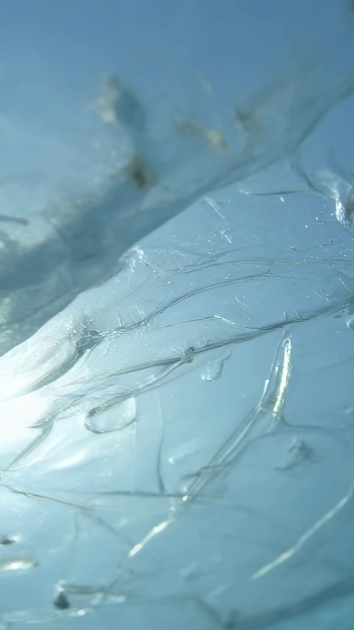 Video verticale: Inquadratura panoramica che rivela un primo piano di una pellicola in gel, esponendo fibre, detriti e bolle d'aria.