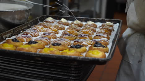 Drizzling-glaze-icing-on-fruit-pastries-at-a-bakery---slow-motion