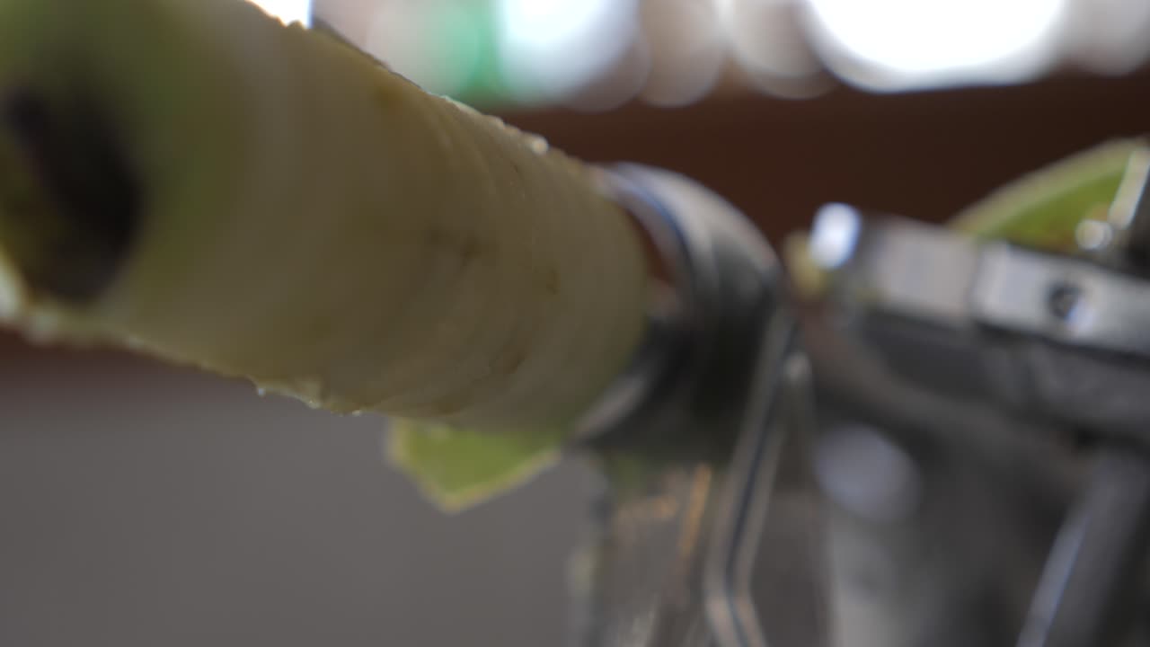 медленный, абстрактный кадр зеленого яблочного ядра, удерживаемого на металлическом устройстве на домашней кухне с висящей кожурой