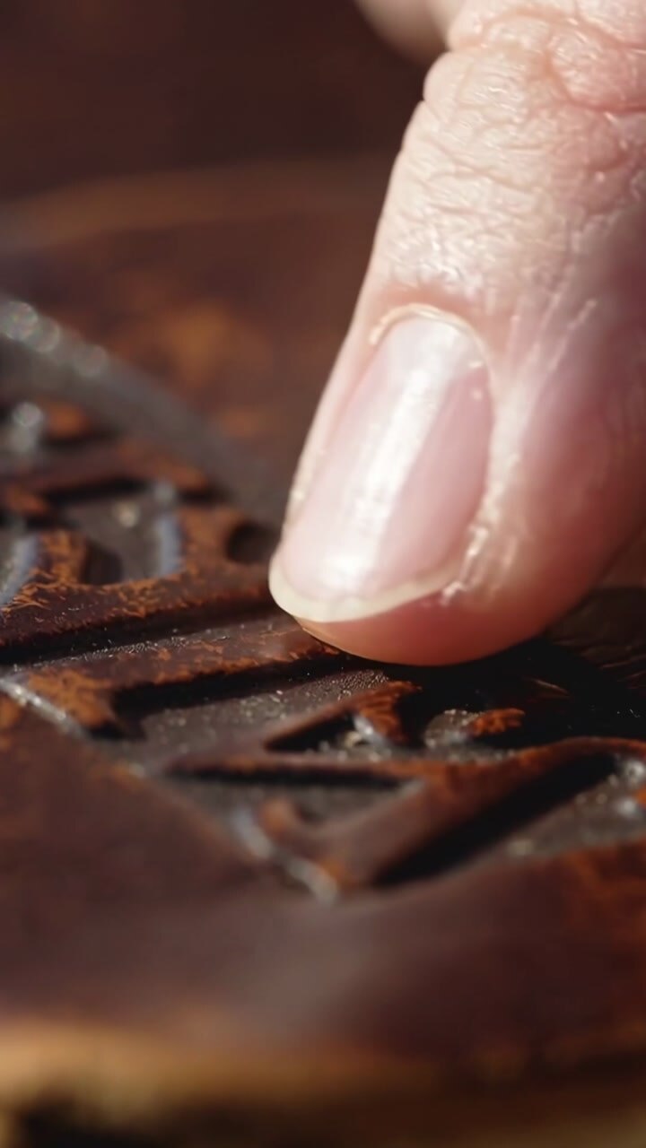 Vertical video: Index fingertip touching sliding embossed letters while checking texture for design