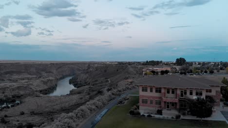 Panorámica-Aérea-Lenta-Y-Tiro-Ascendente-Sobre-Un-Pequeño-Edificio-Junto-Al-Cañón-Del-Río-Snake-En-Twin-Falls,-Idaho-Al-Atardecer