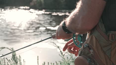fly fisherman slowly reeling in his line at a lake