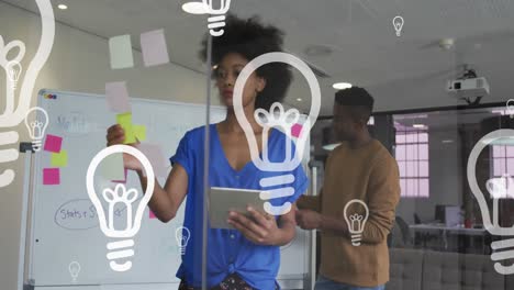 animation of bulb icons floating over african american male and female business colleagues in office