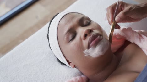Beautician-applying-beauty-mask-on-face-of-african-american-plus-size-woman,-unaltered,-slow-motion