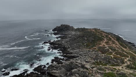 Drone-Flying-Low-Over-Rocky-Shore-In-Open-Blue-Ocean,-Puente-Alto,-Chile