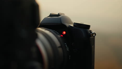 a close-up view of a digital camera with a red indicator light active, suggesting it's recording or in a specific mode