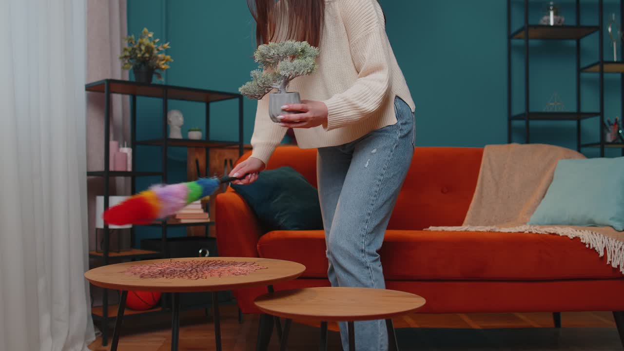 радостная молодая женщина пылила мебель, заботилась о гигиене, используя красочный пылесос в гостиной дома