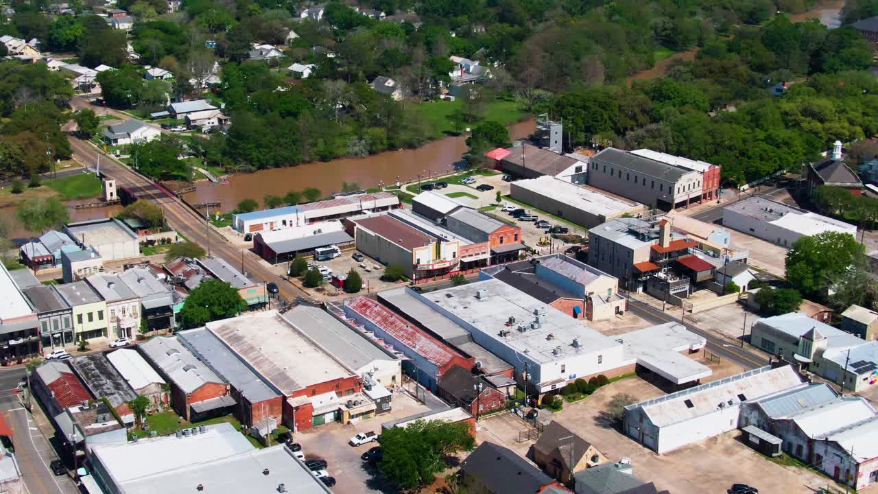 Drone rotation over downtown New Iberia, LA, showing industrial and retail buildings, the museum, theatre, Bayou Teche, nearby lodging, and residential areas across the bridge
