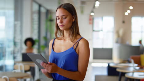 joven mujer de negocios sonriente de pie en una moderna oficina de plan abierto ocupada usando una tableta digital