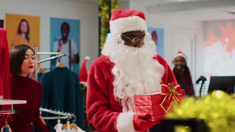 Worker-wearing-Santa-Claus-outfit-in-xmas-ornate-clothing-store,-inviting-customers-to-participate-in-Christmas-raffle-competition-in-order-to-win-promotional-prize-during-festive-holiday-season