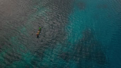 Birds-Eye-Aerial-View-on-People-in-Boat-with-Outrigger-in-Blue-Tropical-Sea-Water