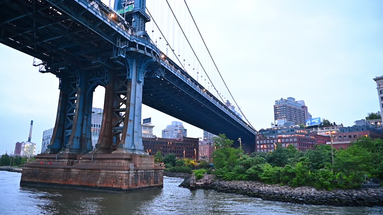 Approaching the support base of the Manhattan Bridge. Low angle view at the bridge during the travel by the riverboat. New York, USA