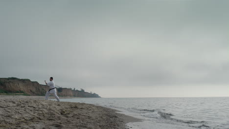 Hombre-De-Karate-Profesional-Entrenando-En-La-Playa-De-Arena.-Atleta-Practicando-Taekwondo.