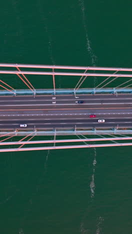 speed motorways on the whitestone bridge in new york. flying high over the bridge construction at the backdrop of turquoise water of river. vertical video