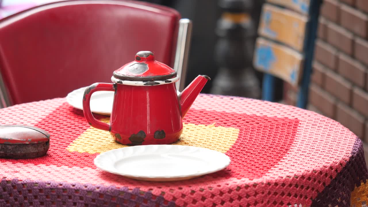 A red teapot on a crocheted tablecloth